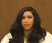 a woman with long black hair is making a funny face while wearing a white shirt .