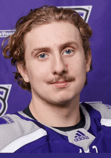 a young man with a mustache wearing a purple adidas jersey