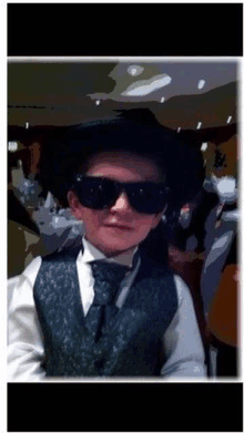 a young boy wearing a hat and sunglasses is standing in front of a table .