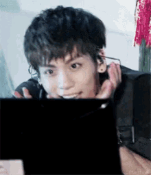 a young man is sitting in front of a laptop computer and smiling .