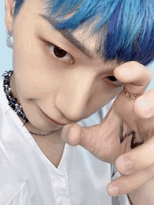 a close up of a person with blue hair taking a selfie with their hand .