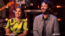 a man and a woman are sitting next to each other on a stage with a nbc logo in the background