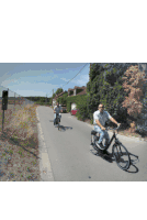 two men are riding bicycles down a road in front of a sign that says ' a ' on it