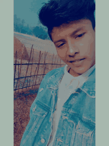 a young man wearing a blue denim jacket and white shirt poses for a picture