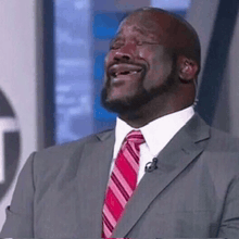 a man in a suit and tie is laughing with his mouth open