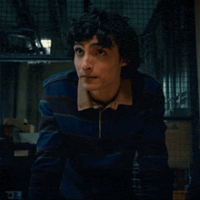 a young man wearing a striped shirt looks at the camera