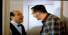 two men are laughing while standing next to each other in a room .