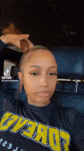 a woman is sitting in the back seat of a car with her hair in a ponytail .