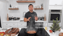 a man cooking in a kitchen with a christmas tree in the background
