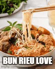 a bowl of noodles with chopsticks in it and the words `` bun rieu love '' written on it .