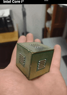 a hand is holding a small intel core i3 processor