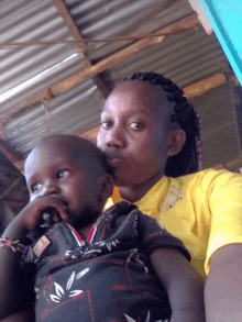 a woman wearing a yellow shirt is holding a baby