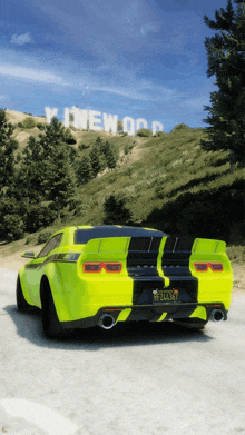 a neon yellow car is driving down a road in front of a sign that says ' hollywood '