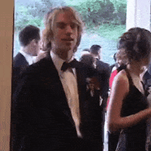 a man in a tuxedo is standing next to a woman in a dress