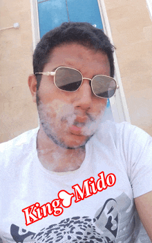 a man wearing sunglasses and a white shirt that says king mido