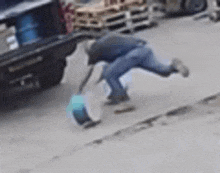 a man is playing with a blue ball on the sidewalk .