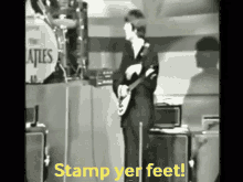 a black and white photo of a man playing a guitar with the words stamp yer feet on the bottom