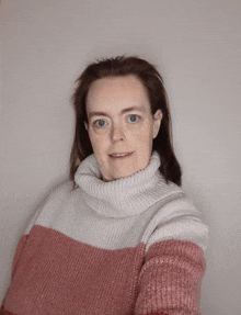 a woman wearing a pink and white striped sweater with a turtleneck