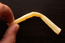 a person is holding a french fry that is bent