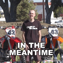 a man wearing a dirt bike shirt stands in front of two dirt bikes with the words in the meantime written below him