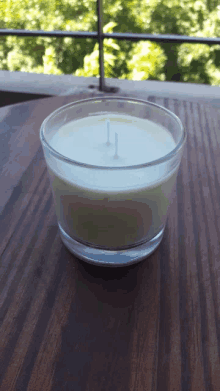 a candle is sitting on a wooden table with a balcony in the background