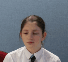 a girl wearing a white shirt and a tie with her eyes closed