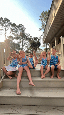 a group of children are sitting on a set of stairs and giving the peace sign