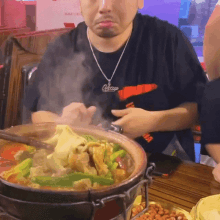 a man wearing a necklace that says chicago is eating a pot of food