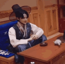 a man in a traditional korean costume is sitting at a table with a teapot .