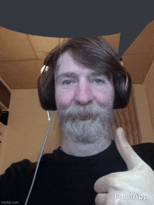 a man with a beard wearing headphones giving a thumbs up sign