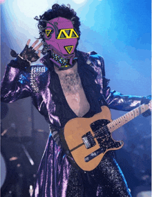 a man in a purple suit is playing a guitar and wearing a purple mask