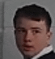 a close up of a young man wearing a suit and tie .