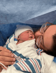 a woman wearing glasses holds a newborn baby