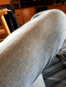 a close up of a person 's leg with a remote control behind it