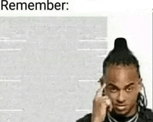 a man with dreadlocks is holding his finger to his forehead while talking on a cell phone .