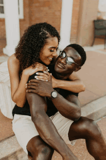 a man is carrying a woman on his shoulders and the woman is wearing sunglasses