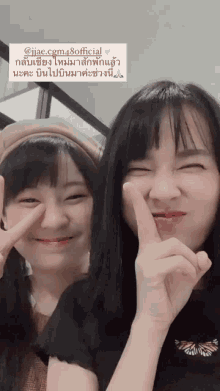 two asian girls are posing for a picture with their fingers on their faces