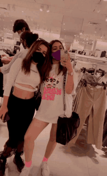 two girls are posing for a picture in a clothing store