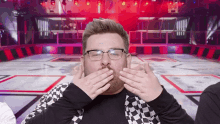 a man wearing glasses and a checkered jacket is blowing a kiss