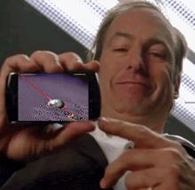 a man in a suit is holding a cell phone with a picture of a ball on it