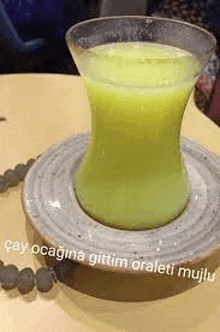 a cup of green liquid is sitting on a plate on a table .