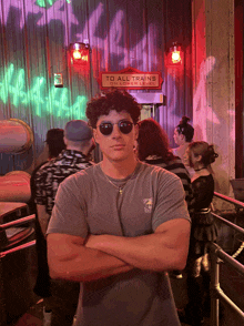 a man wearing sunglasses is standing in front of a sign that says to all trains on lower level