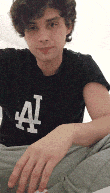 a young man is wearing a black shirt with the letter a on it