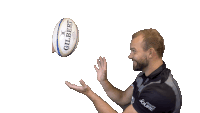 a man is throwing a gilbert rugby ball in the air