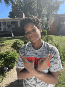 a boy wearing a shirt that says blessed on it stands in front of a house