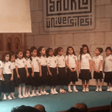 a group of young girls are standing on a stage in front of a sign that says universitesi