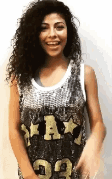 a woman with curly hair is wearing a sequined tank top that says star on it