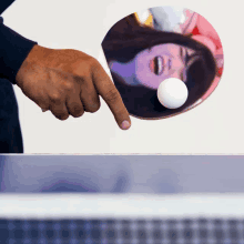 a person playing ping pong with a picture of a girl on the paddle