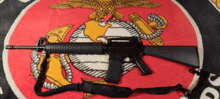 a rifle with a sling is laying on a blanket with a marine emblem on it