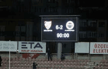 a soccer game is being played in a stadium with a scoreboard showing the score of 6-2 .